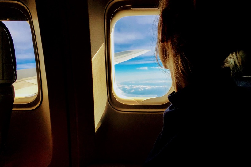 garota indo estudar fora olhando pela janela do avião