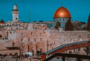 Inovação em Israel: uma foto da cidade de Israel, com construções em tijolos em uma cor alaranjada e a cúpula dourada, conhecida como Domo da Rocha. Perto desse monumento, algumas árvores complementam a paisagem.