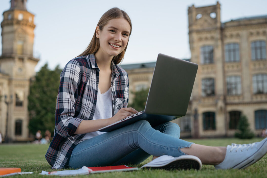 menina sentada com laptop estudando e mostrando os benefícios de viver no exterior