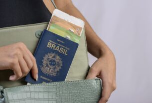 Uma pessoa guarda o passaporte brasileiro em uma bolsa, além de outros documentos, como passagem aérea e documentos pessoais.