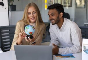 Uma mulher e um homem conversando com um globo terrestre na mão, como se estivessem interessados na carreira de negócios internacionais.